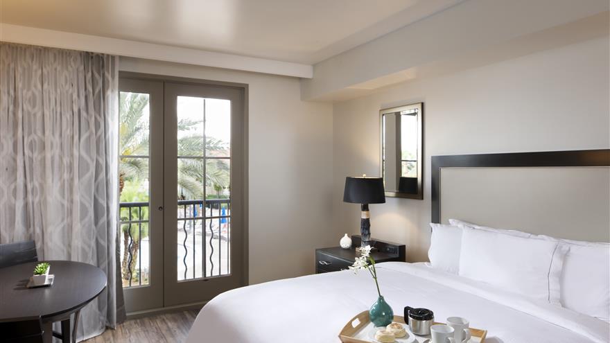Cozy bedroom with a balcony at  Las Palmeras, a Hilton Grand Vacations Club in Orlando, Florida.