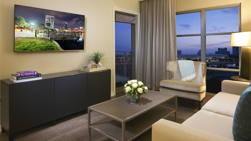 Living room with LCD flat-panel TV and sofa sleeper with a window view of Orlando at  Las Palmeras, a Hilton Grand Vacations Club in Orlando, Florida.