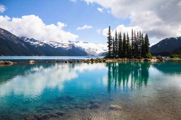 Stunning glacial fed lake, snow-capped mountains in the distance, Whistler, British Columbia, Canada. 