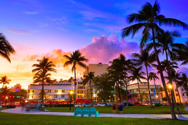 Ocean Drive glowing at dusk, palm tree silhouettes against neon glow, Miami Beach, Florida. 