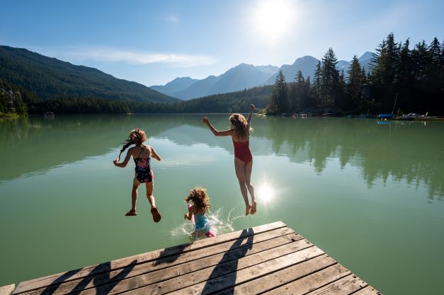 Kids jumping off dock into mountain lake, Whistler, British Columbia, Canada. 