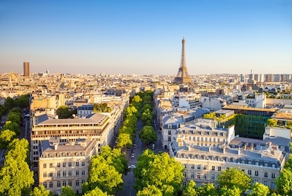 Aerial image of Paris, France during the day, with the city lit in a soft golden glow and the Eiffel Tower in the distance.