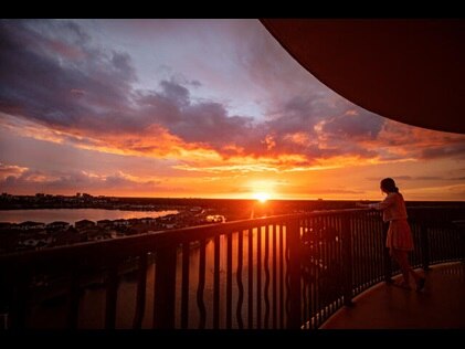 Woman admiring sunset painted skies from her Hilton Grand Vacations Orlando resort balcony. 