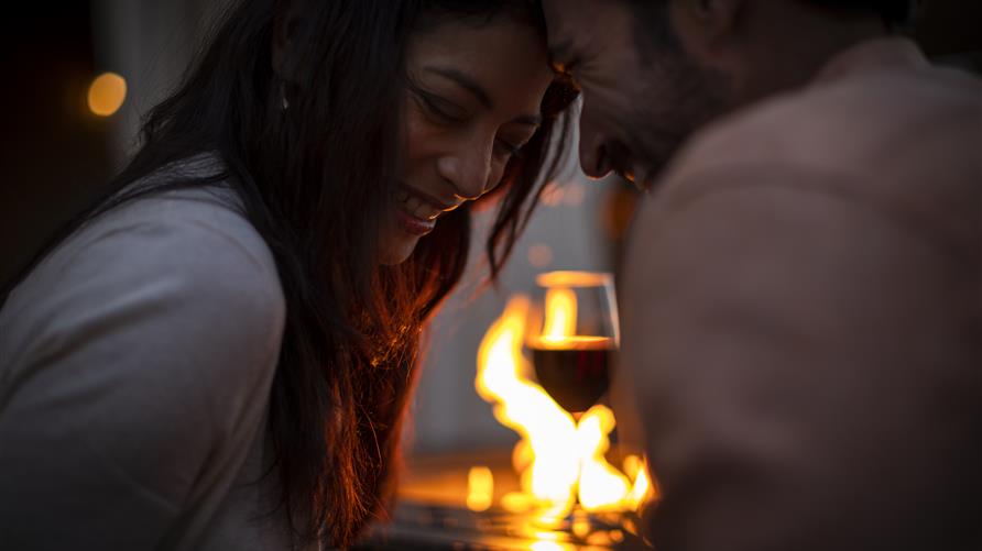 Couple cuddling by fire with wine