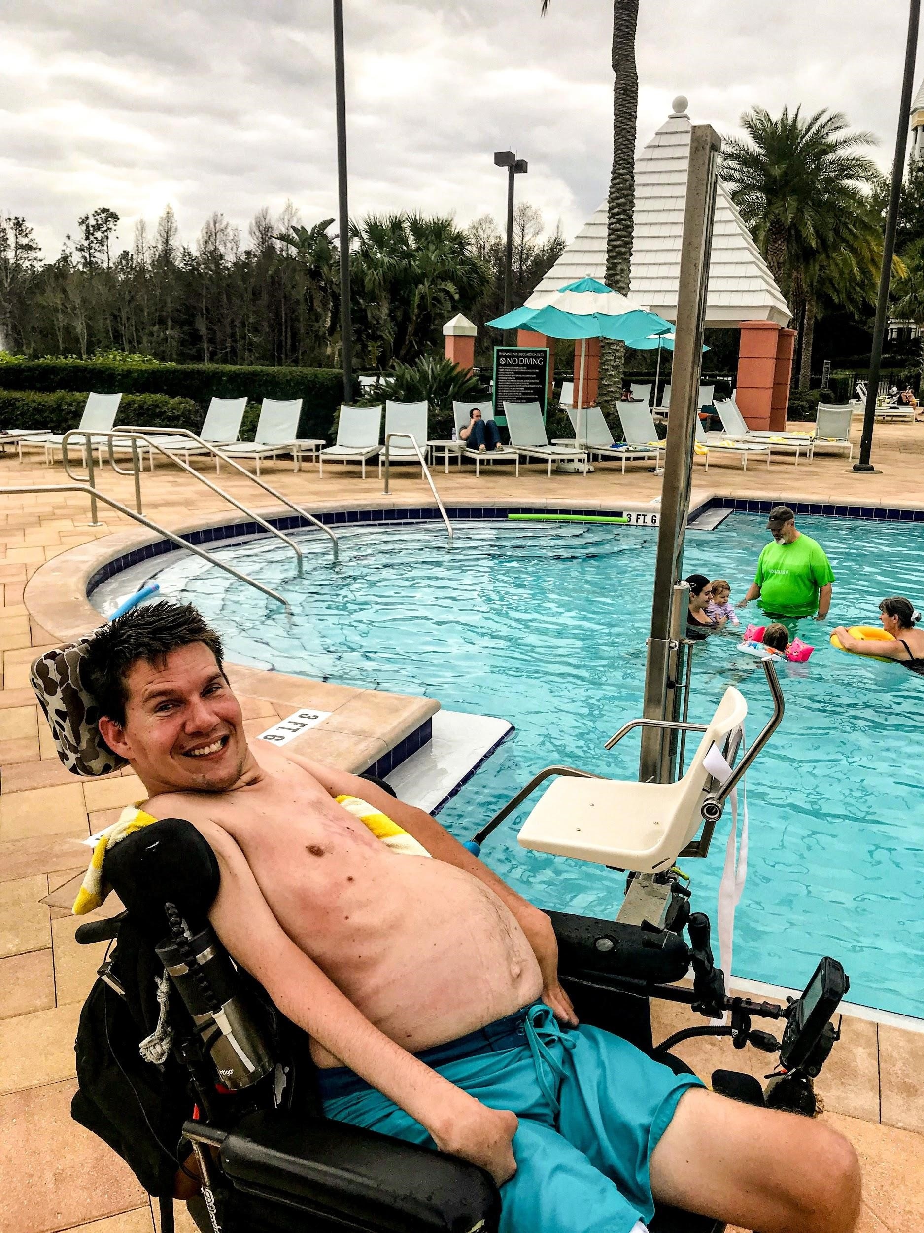 A Hilton Grand Vacations Owner in a wheel chair excited about the handicap pool lifts at the Hilton Grand Vacations at SeaWorld resort pool. 