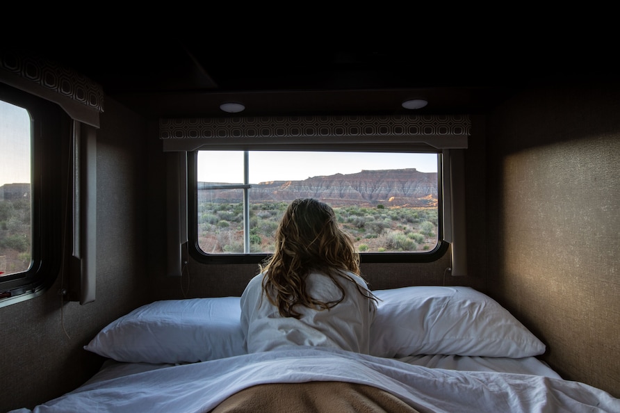 Woman looking out El Monte RV Window into desert.