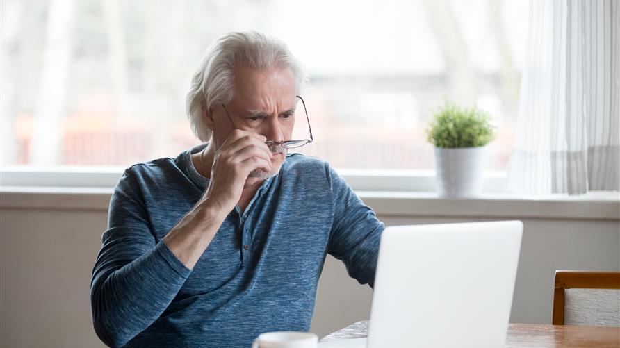 A mature man inspecting a possible travel scam while on the computer. 