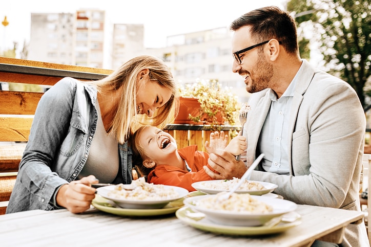 A happy family laughing and engaging at dinner during a digital detox challenge. 