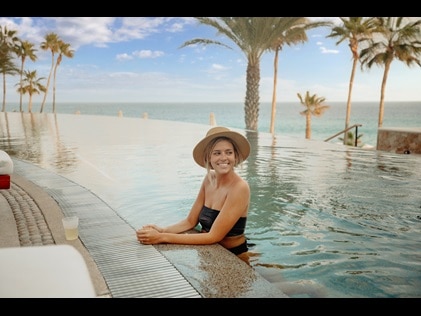 Woman smiling while enjoying the infinity pool at the new Los Cabos resort, La Pacifica by Hilton Club. 