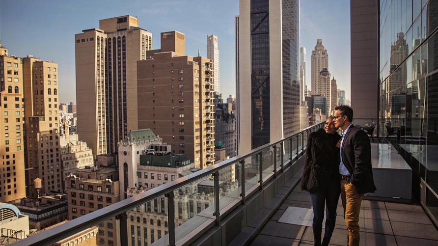 A couple enjoying the New York City skyline on a balcony at 57th West by Hilton Grand Vacations. 