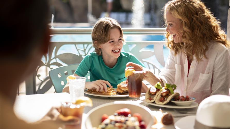 Happy family enjoying lunch poolside at Hilton Grand Vacations at SeaWorld in Orlando, Florida. 