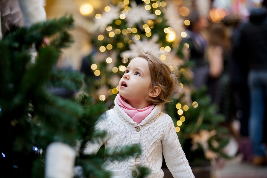 Little girl looking up in awe at Christmas lights.