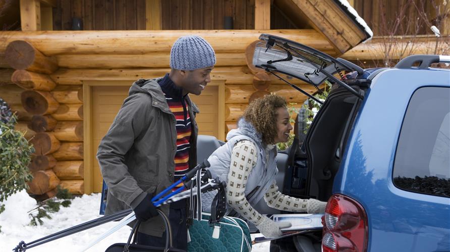 Couple excitedly packing their car for a Christmas vacation.