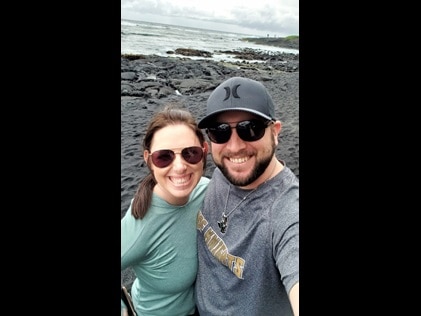 Happy couple taking at selfie at Punalu'u Black Sand Beach in Hawaii while on vacation with Hilton Grand Vacations. 