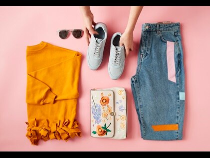 Overhead shot of a woman laying out an outfit including shoes, pants, shirt and accessories. 