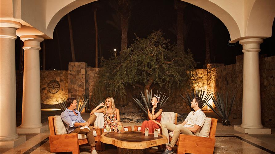 A group of friends enjoying cocktails in an open air lobby at La Pacifica by Hilton Club in Los Cabos, Mexico. 