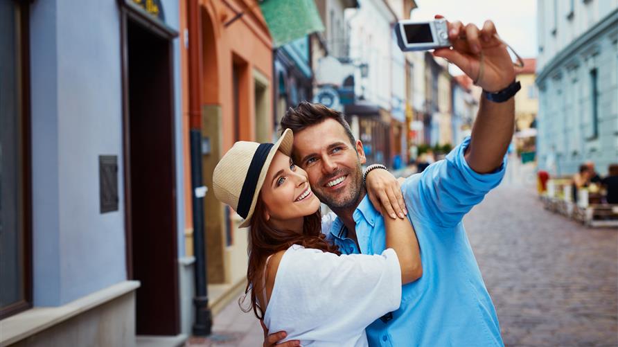 Couple smiling and snapping a selfie while on vacation.
