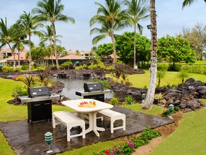 Barbeques and picnic tables surrounded by lush landscaping at The Bay Club Waikoloa Beach Resort. 