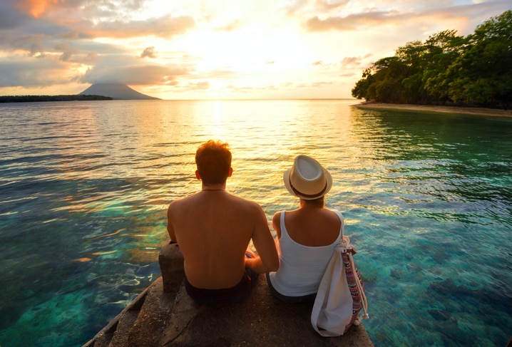 Couple on a romantic getaway enjoying the sunset overlooking the water. 