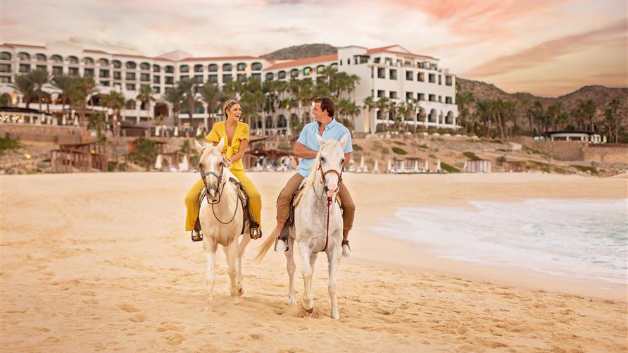 Couple horseback riding along the beach in Los Cabos, Mexico while on vacation at La Pacifica by Hilton Club. 