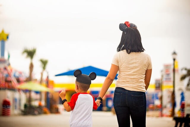 Mother and son walking hand in hand wearing Micky Mouse ears while on vacation in Orlando, Florida. 