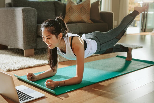 Young women exercising to stay healthy on vacation using the computer a suite living room. 