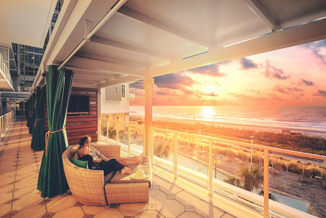 Couple cuddled up watching the sunset at Ocean 22 by Hilton Grand Vacations in Myrtle Beach, South Carolina. 