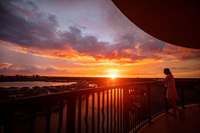 Woman watching the sunset on balcony at Hilton Grand Vacations in Orlando, Florida. 