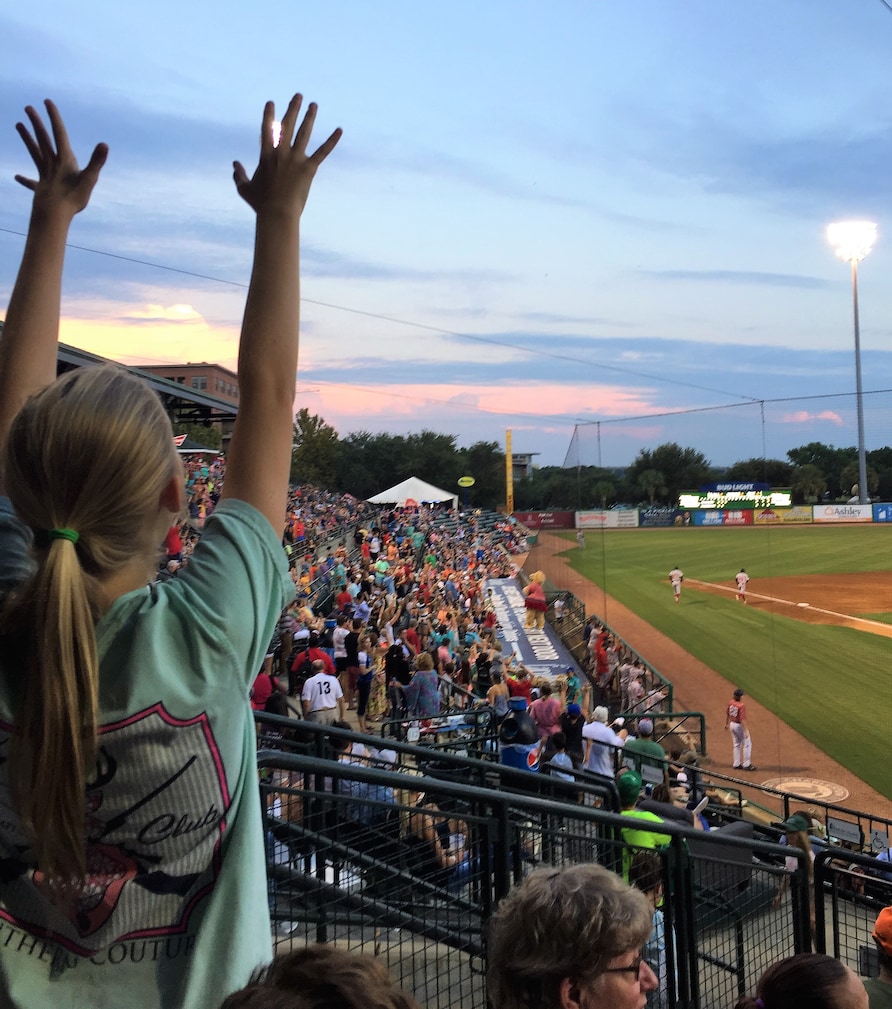 Young girl doing the wave at a River Dogs baseball game in Charleston, South Carolina. 