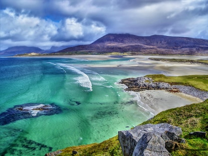 Aerial view of emerald seas and lush green cliffs at Luskentyre Beach Isle of Harris, Scotland.