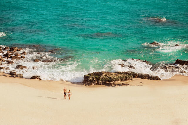 Aerial view of couple walking along the beach in Los Cabos, Mexico. 
