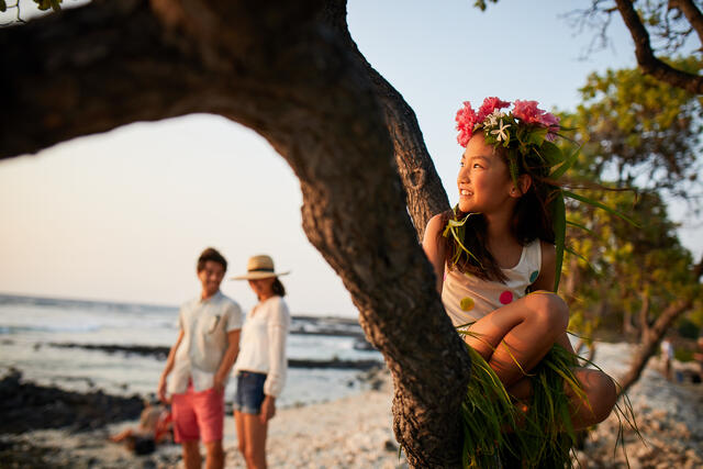 Young girl in flower crown gazing at the Pacific ocean from the beach in Hawaii. 