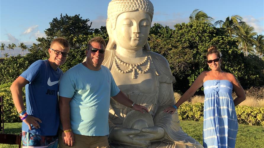 Hilton Grand Vacations Owner with son and wife posing with Buddha at Ocean Tower by Hilton Grand Vacations on the Big Island of Hawaii. 