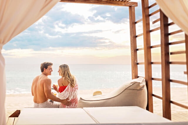 Couple enjoying at Hilton Grand Vacations beach cabana while on a family beach vacation in Los Cabos, Mexico. 