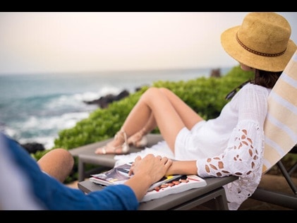 Couple holding hands overlooking the Pacific ocean at Ocean Tower by Hilton Grand Vacations Big Island resort in Hawaii. 