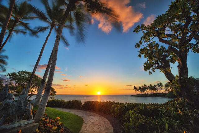 View of the sun sinking into the ocean from walkway in Hilton Waikoloa Village on the Big Island of Hawaii. 
