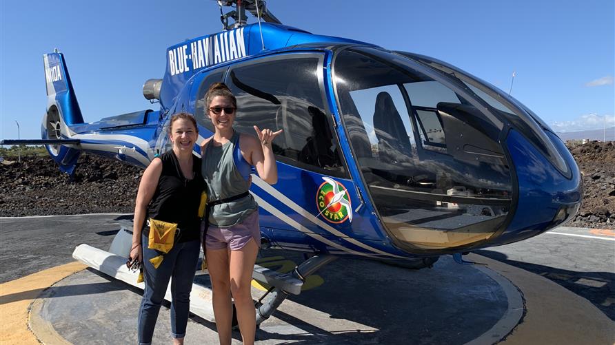 Two women posing with a helicopter on vacation in Hawaii on the Big Island. 