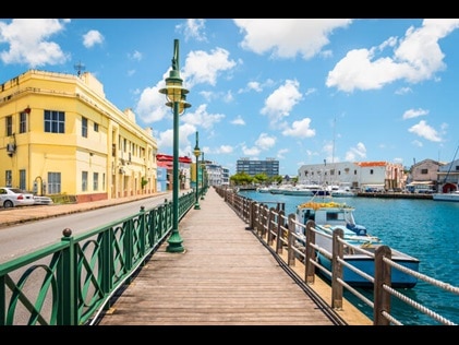 Shot of Bridgetown Boardwalk with buildings on one side and water and boats on the other in Barbados. 