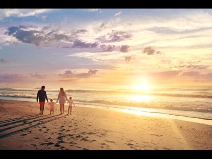 Family of four walking hand in hand at sunset on Myrtle Beach in South Carolina.
