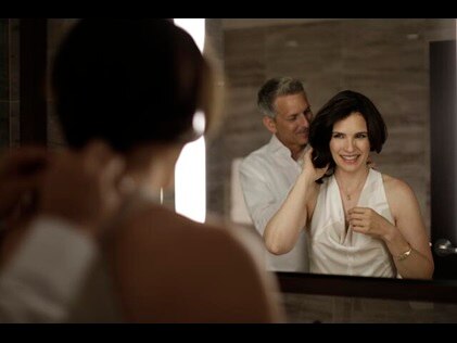 Man clasping woman's necklace in bathroom at The Residences by Hilton Club, a New York City timeshare. 
