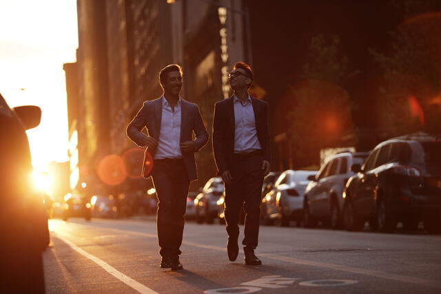 Two men walking down Midtown Manhattan street at sunset in New York City. 