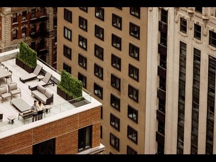 Couple looking down on the city below from rooftop terrace at The Quin by Hilton Club in New York City. 