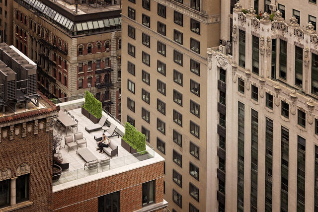 Aerial shot of couple sitting on roof top terrace at The Quin by Hilton Club in New York City. 
