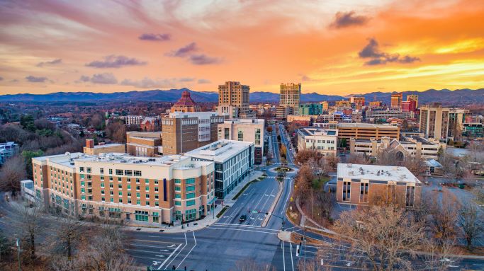 Aerial shot of downtown Asheville, North Carolina, with orange sunset painted skies.
