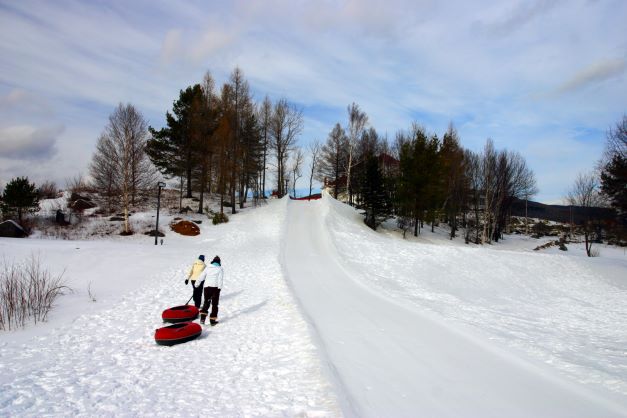 Kids pulling snow tubes of a snow covered New Hampshire hill.