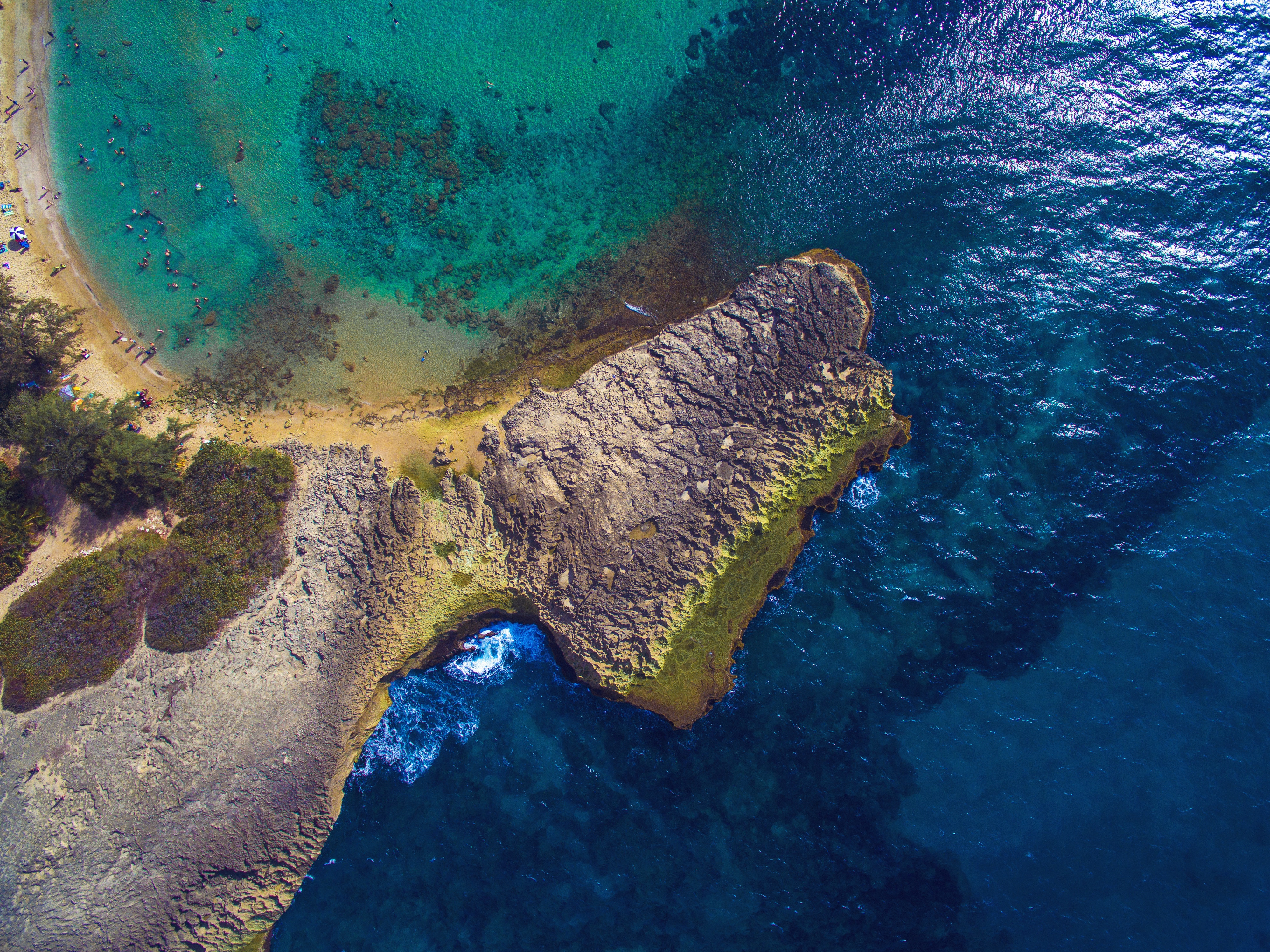 Aerial shot of a crescent shapped beach dotted with beachgoers in Puerto Rico. 