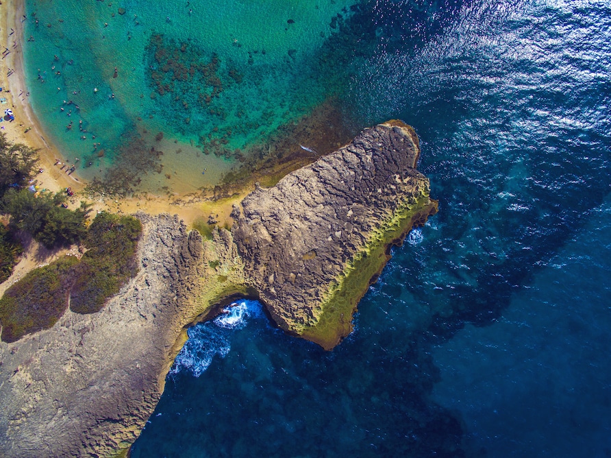 Aerial shot of a crescent shapped beach dotted with beachgoers in Puerto Rico. 