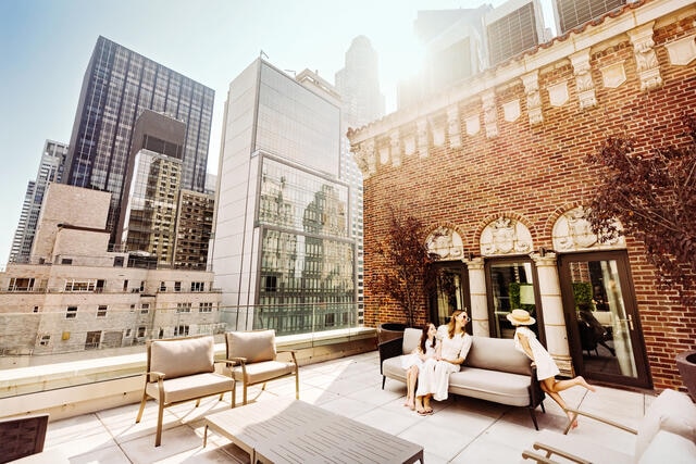 Mother and young daughters enjoy the rooftop terrace at The Quin by Hilton Club, midtown Manhattan, New York.