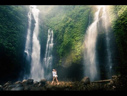 Couple embracing in a kiss in front of pictureque waterfall, Bali, Indonesia. 