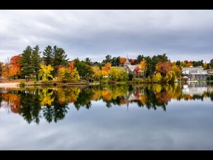 Gorgeous panorama of Lake Placid reflecting fall foliage colored trees, New York. 